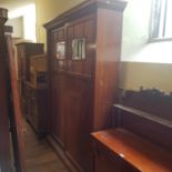 A 1920's mahogany two door wardrobe, the sliding doors inset with mirrored panels, 222 cm high x 100