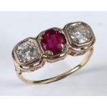 A yellow coloured metal ring, set a ruby flanked by two diamonds, in a pierced setting, apparently