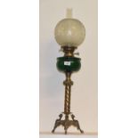 A late 19th/early 20th century brass oil lamp with green glass well, 80 cm high