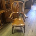 A yew and elm Windsor type kitchen armchair, the splat pierced Christmas trees, on turned legs