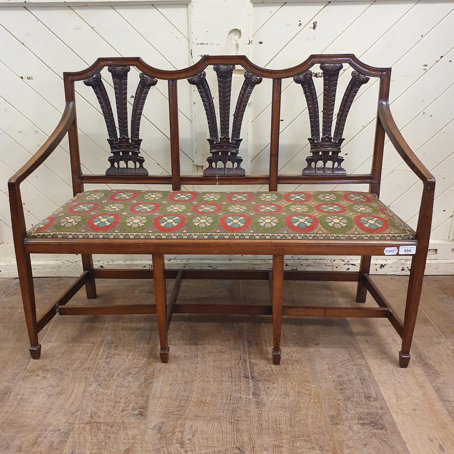 An unusual child's walnut chair back settee, with fleur de lys backs, a drop in seat and tapering