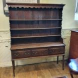 An oak dresser, the three tier plate rack above a base with three frieze drawers, on tapering legs