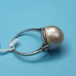 An Art Deco ring, set a cultured blister type pearl in a white coloured metal setting, with a