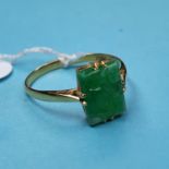 A yellow coloured metal ring, set a carved jade panel, approx. ring size T Report by RB With a