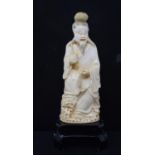 An early 20th century Chinese carved ivory figure, of a man holding a fish, 17.5 cm high, on a