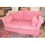 A red two seater sofa Arms worn some staining, no front legs on castors