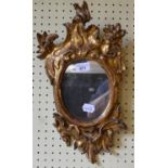 An early 19th century French gilt carved wood oval mirror, in the rococo manner, size 42 x 24 cm