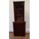 An early 20th century mahogany corner cabinet, with a glazed door above a panel door, 200 cm high
