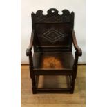 An oak Wainscot chair with carved top rail and back with panel seat on turned legs united by