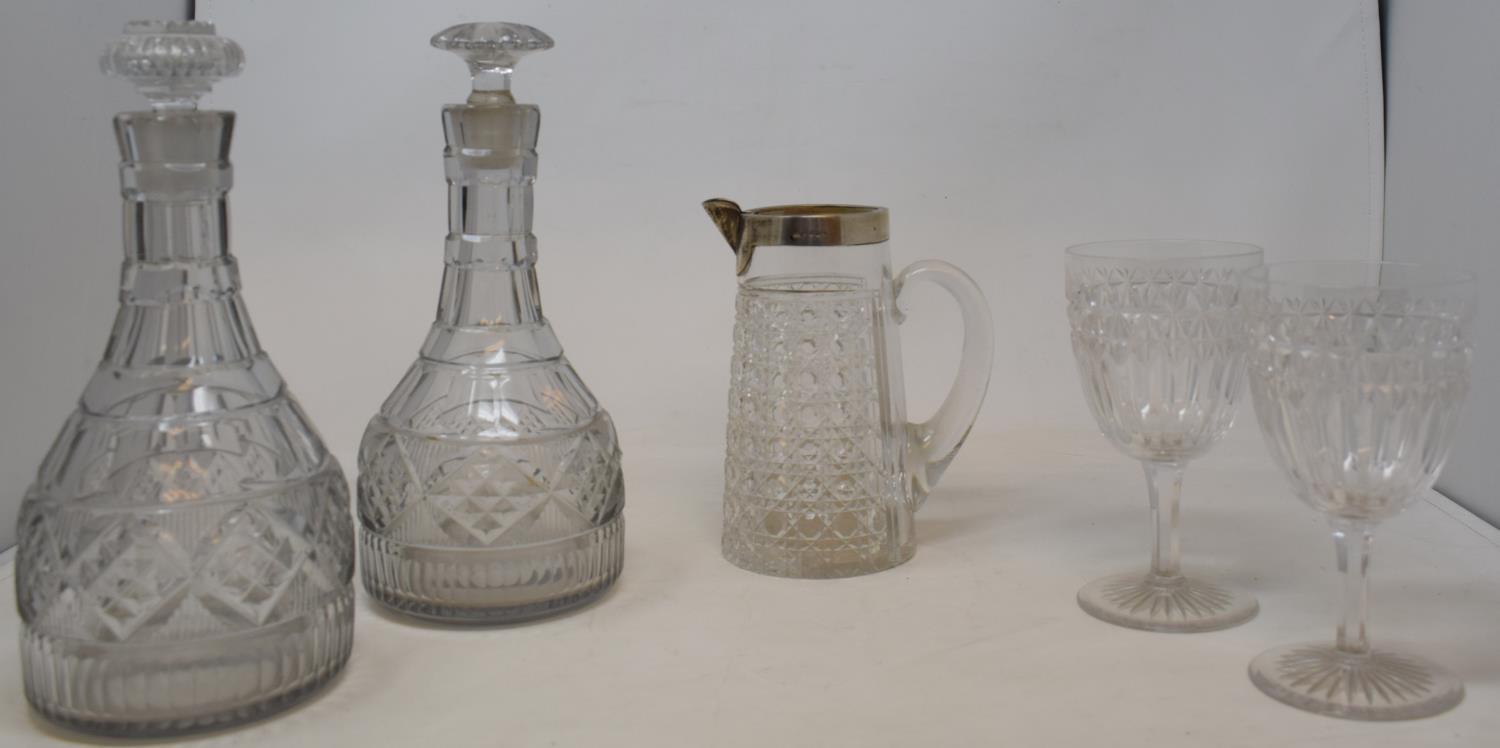 A pair of 19th century glass decanters, a cut glass jug and matching beaker with silver rim and