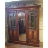 An early 20th century walnut triple wardrobe with central mirror door, flanked by two glazed and