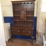 An 18th century style oak dresser, top with plate rack and central cupboard door, base with two