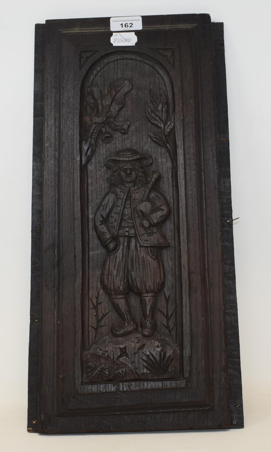 A carved oak panel with a figure holding bagpipes, 48 x 20 cm