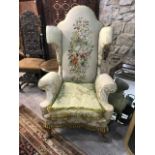 An 18th century style upholstered wing back armchair, on carved cabriole front legs