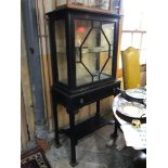 An early 20th century mahogany cabinet on stand, having a glazed door above a drawer on champhered