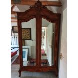 A French walnut armoire, with a pair of mirrored doors, 134 cm wide x 243 cm high