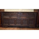 A large oak coffer, carved grapes, flowers and foliage, on stile legs, 168 cm wide Top later
