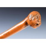 A 19th century folk art walking stick, with carved handle, in the form of a grotesque head, 90 cm