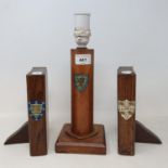 An early 20th century oak lamp base, painted with a crest, 24 cm, and a pair of similar bookends, in