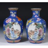 A pair of Chinese famille rose vases, decorated opposing panels of figures and birds, on a blue