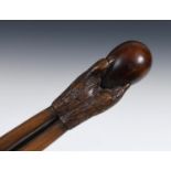 A 19th century folk art walking stick, the handle carved in the form of a talon gripping an egg,