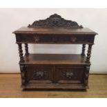 An early 20th century oak buffet, with a carved back, two drawers above an open section and two