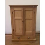 A pine cupboard, with two cupboard doors above a drawer, on plinth base, 102 cm wide !45 cm high,