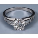 An 18ct white gold and diamond ring, the central stone flanked by channel set diamond shoulders