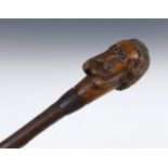 An early 20th century folk art cane, the handle carved in the form of a gentleman with a