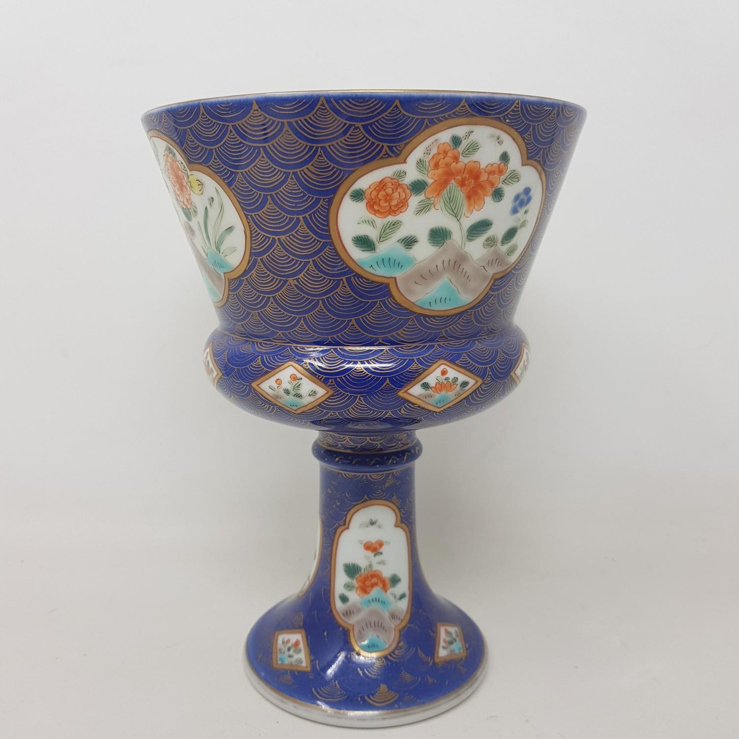 A Japanese porcelain stem cup, decorated flowers in enamel colours on a blue ground with gilt