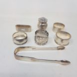 Five silver napkin rings, a pair of silver sugar tongs, and a silver pepperette, 6.4 ozt