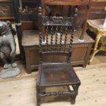 A 17th century style oak hall chair, with carved top rail, panelled seat on turned legs