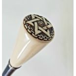 An Early 20th century walking stick, the ivory handle carved with Masonic symbols, on an ebonised