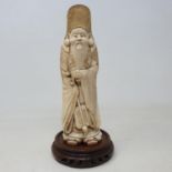 A 19th century Chinese ivory carving of a bearded man in ceremonial robes, holding a turtle,