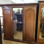 A 19th century plum pudding mahogany triple wardrobe, with central mirrored door, flanked by paneled