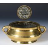 A Chinese polished bronze censer, of compressed circular form, with twin handles, the seal mark