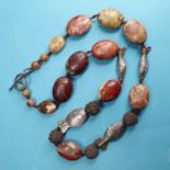 An early 20th century necklace, with carved hardstone oval beads and white metal fish