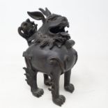 A Chinese bronze censer, in the form of a Dog of Fo, with a hinged head, tail repaired, 15 cm high