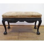 A 19th century mahogany footstool, with foliate carved frieze, on cabriole legs on ball and claw