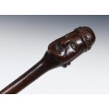 An early 20th century folk art walking stick, the handle carved in the form of a king, with bone
