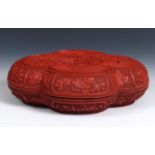 A Chinese red cinnabar lacquer box, of lobed oval form, the cover decorated figures flying a kite,