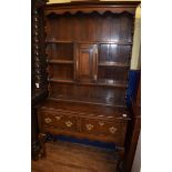 An 18th century style oak dresser, top with plate rack and central cupboard door, base with two