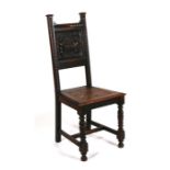 A continental oak hall chair with carved panel back depicting two figures drinking at a table.