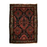 A Persian woollen hand knotted rug with stylised design within foliate borders, on a blue ground,