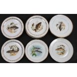 A quantity of Limoges plates, each decorated with fish within a gilded border, 24cms (9.5ins)