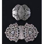 An unmarked continental white metal pierced belt buckle; together with a similar silver plated