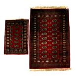 A Bokhara woollen hand knotted rug with two rows of repeated medallions on a red ground, 158 by 96.