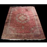 A machine made carpet, with central floral medallion on a red ground. 371 by 249cm (146 by 98 ins)