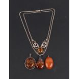 A yellow metal mounted oval amber pendant; together with two silver mounted amber pendants and