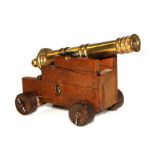 A small brass Signal Cannon mounted on a wooden carriage with wooden wheels. Barrel length 14.